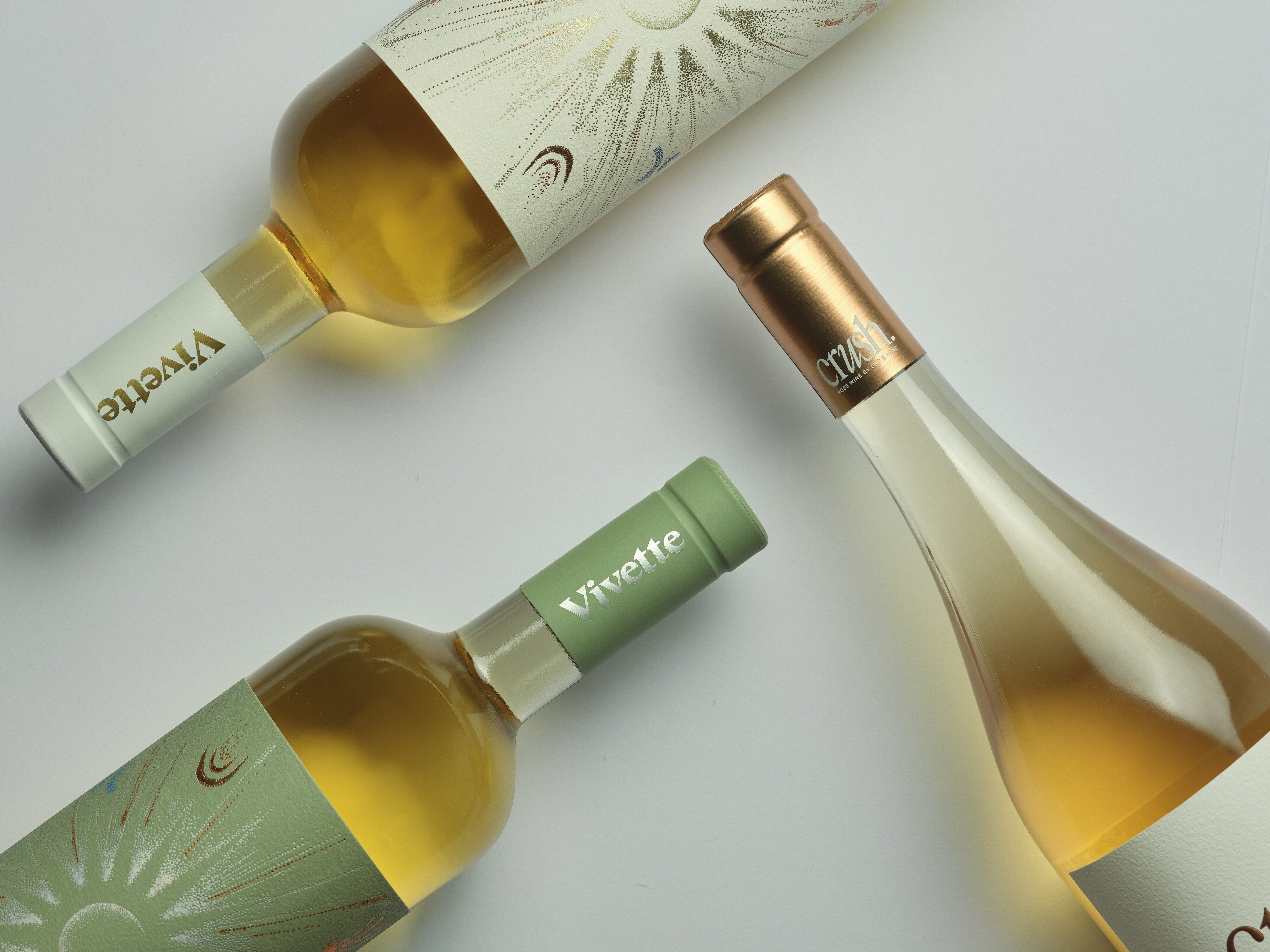 Botellas de Vivette Chardonnay, Vivette Gewürztraminer y Crush sobre fondo claro